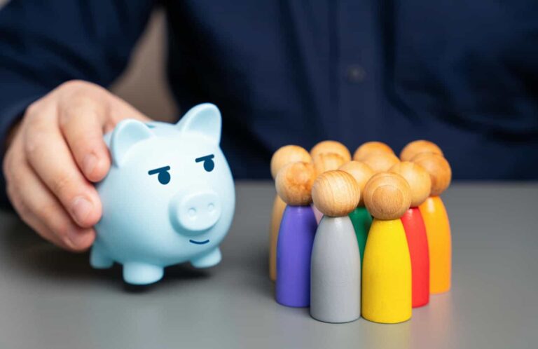 a-businessman-holds-a-blue-piggy-bank-next-to-a-gr