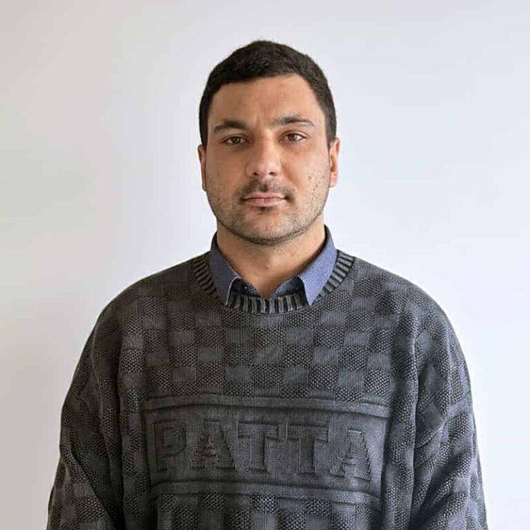 Manager Samuel Mir from SMSF Warehouse, wearing a patterned sweater, standing against a plain background, representing the accounting team and cryptocurrency assistance.