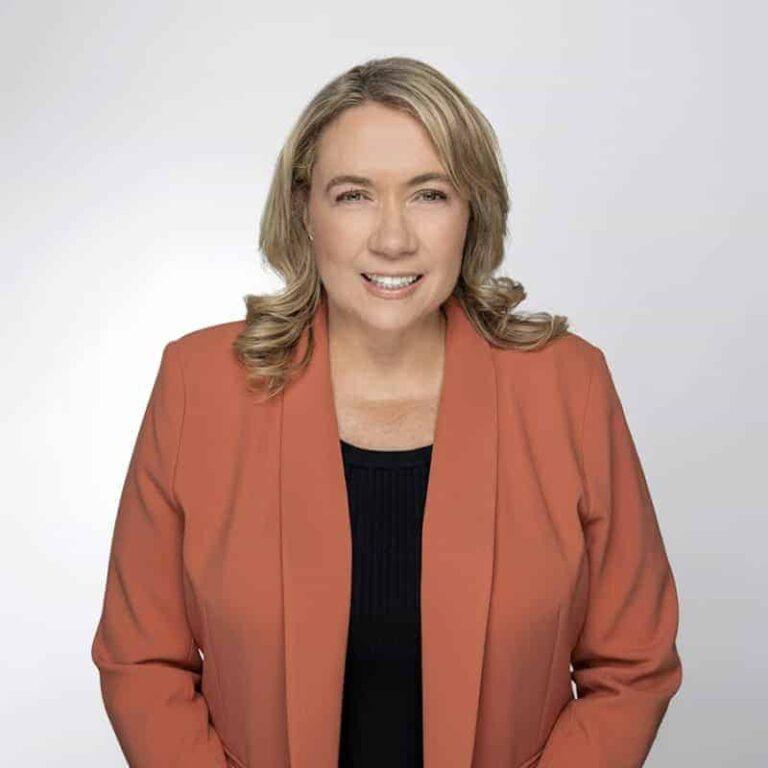 Yvette Preller, Senior Finance Manager at SMSF Warehouse, smiling in a professional setting, wearing an orange blazer, representing financial expertise and team leadership.