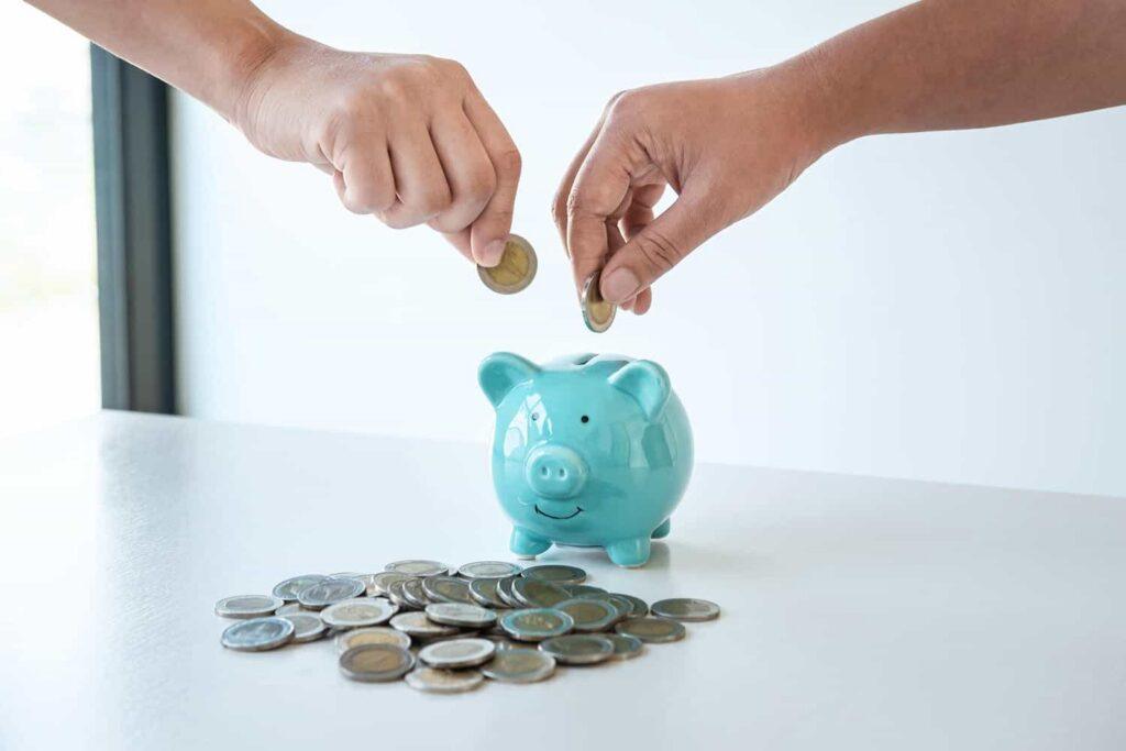 image of hands putting coins into piggy bank
