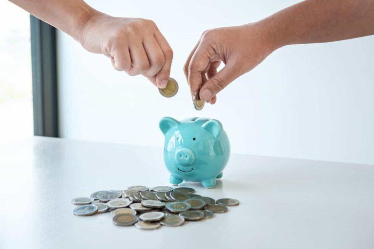 image of hands putting coins into piggy bank