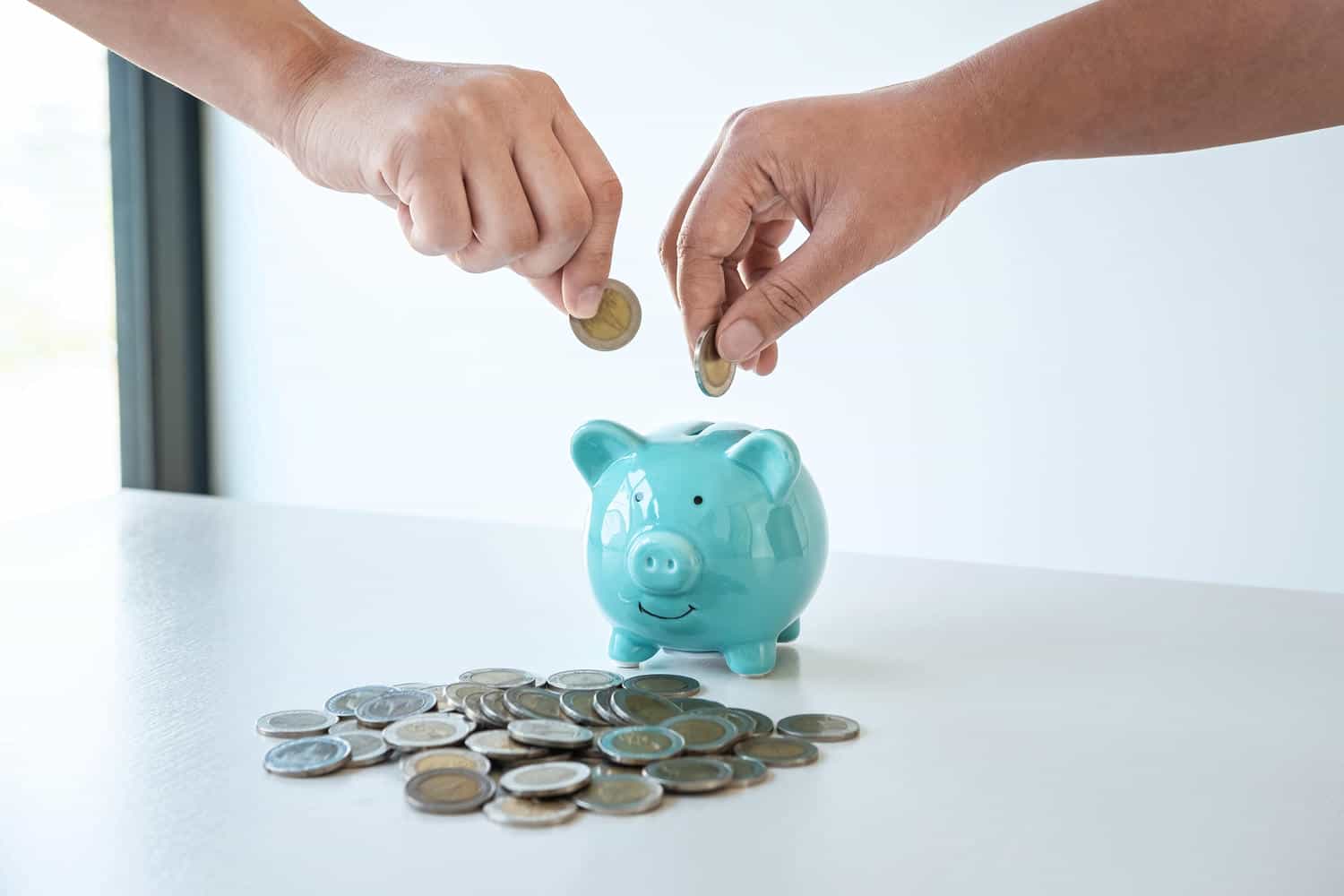 image of hands putting coins into piggy bank